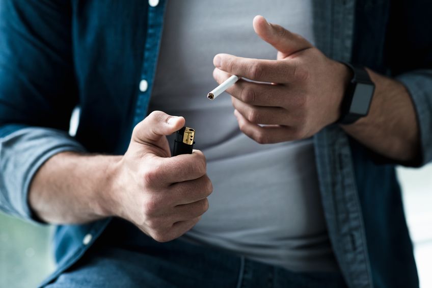 Man smoking a cigarette at home as he's unable to break the habit