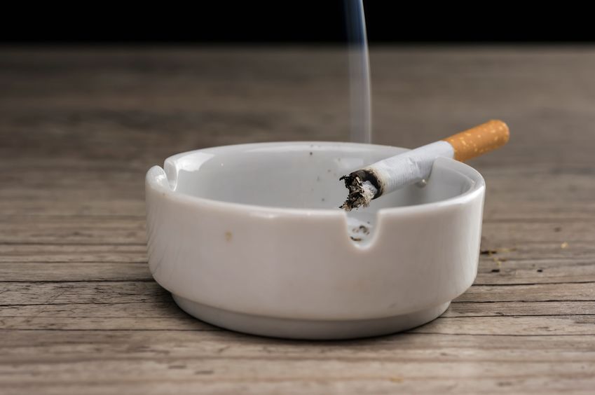 Lit cigarette burning in ashtray