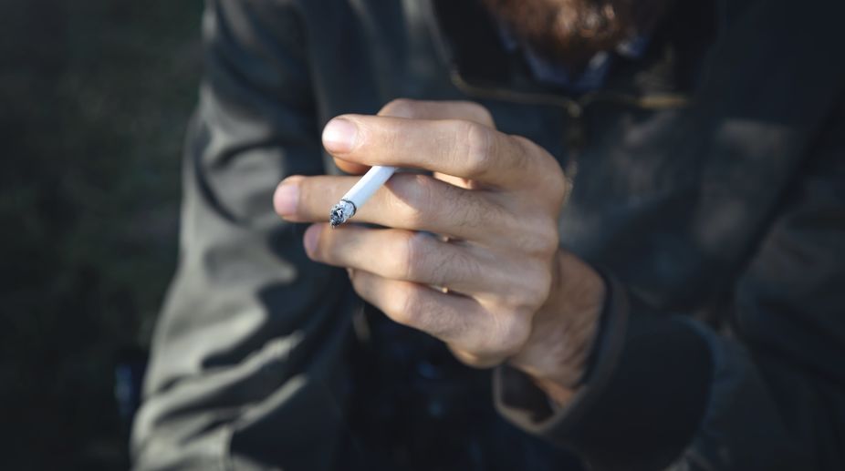 Man smoking a cigarette as it rests between his fingers